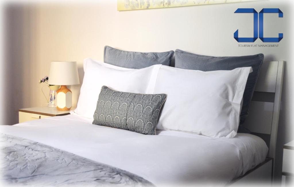ein weißes Bett mit weißen Kissen und einem grauen Kissen in der Unterkunft Riverside (with 3 Bedrooms) by JC in Porto