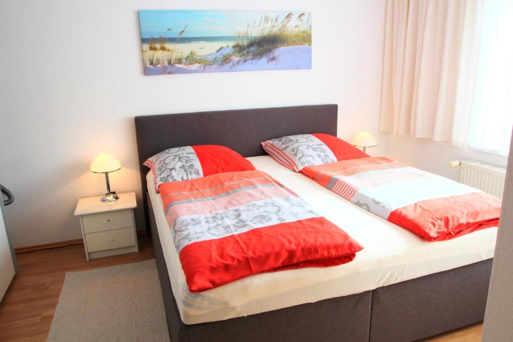 ヴァーネミュンデにあるFerienwohnungen Sonnenstrandのベッドルーム1室(ベッド2台、赤と白のシーツ付)