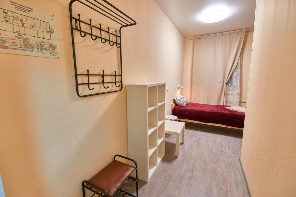 Habitación pequeña con cama y estante en Klukva Hostel, en Syktyvkar