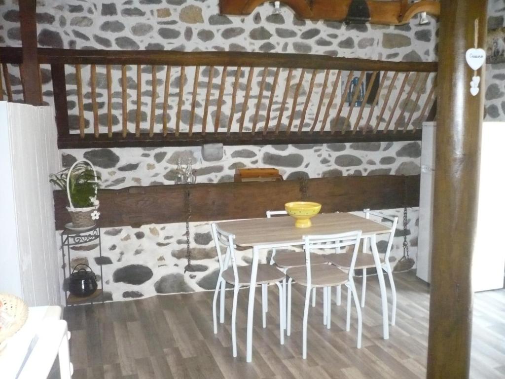 uma mesa e cadeiras num quarto com uma parede de pedra em lecurieabedous em Bedous