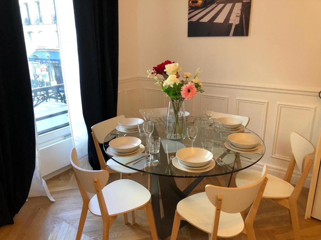 une table de salle à manger avec un vase de fleurs dessus dans l'établissement RESIDENCE MONTORGUEIL, à Paris