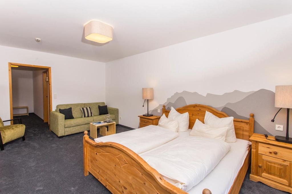 a bedroom with a bed and a living room with a couch at Alpengasthof Hörnlepass in Riezlern