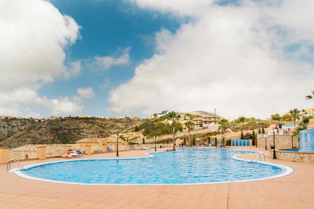 a large swimming pool with a mountain in the background at Villas Guzman - Apartamento Velazquez in Benitachell