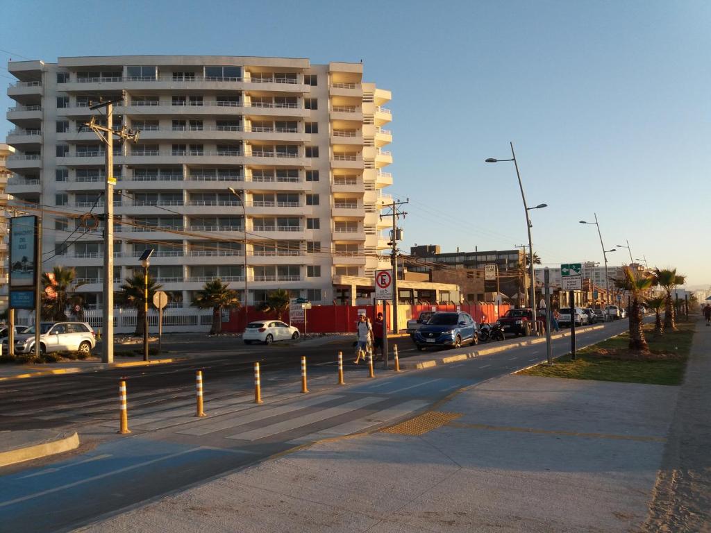 una calle de la ciudad con coches aparcados frente a un edificio alto en Departamento frente al mar, en La Serena