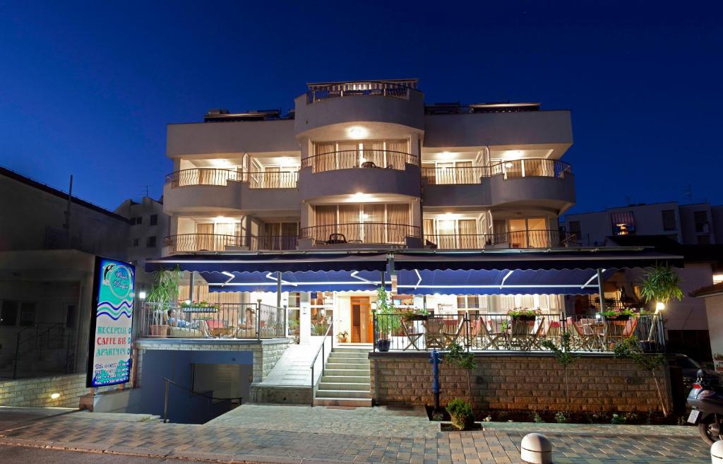 a tall building with blue umbrellas in front of it at Studio Apartmani Bijeli Delfin in Biograd na Moru