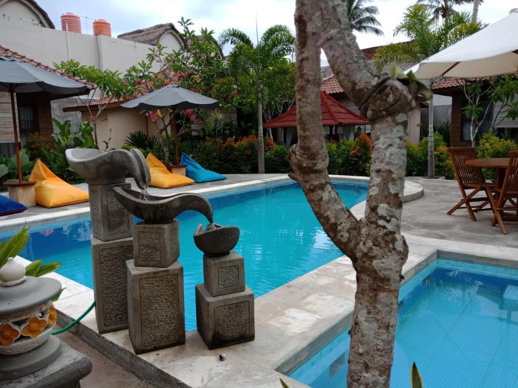 una piscina en un complejo con dos esculturas al lado en Zifa Kuta Lombok, en Kuta Lombok