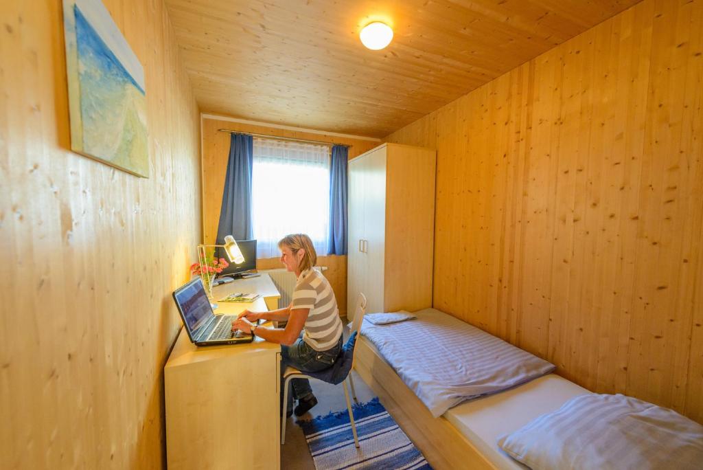 eine Frau, die an einem Schreibtisch in einem Zimmer mit einem Laptop sitzt in der Unterkunft Gästehaus Aquilin in Sankt Pölten
