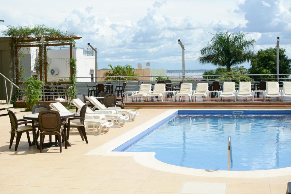 a swimming pool with chairs and a table at De la Trinidad Hotel in Encarnación