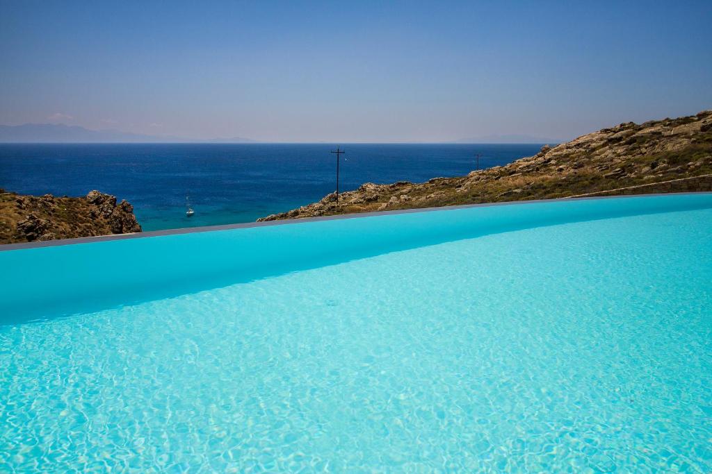 a blue pool with the ocean in the background at Villa ANAIS 2 MYKONOS in Elia Beach