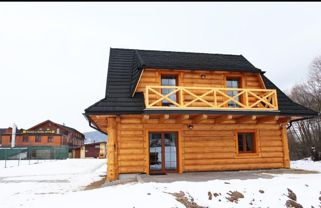 une cabane en rondins dans la neige avec un balcon dans l'établissement Chatky JOSU, à Zuberec