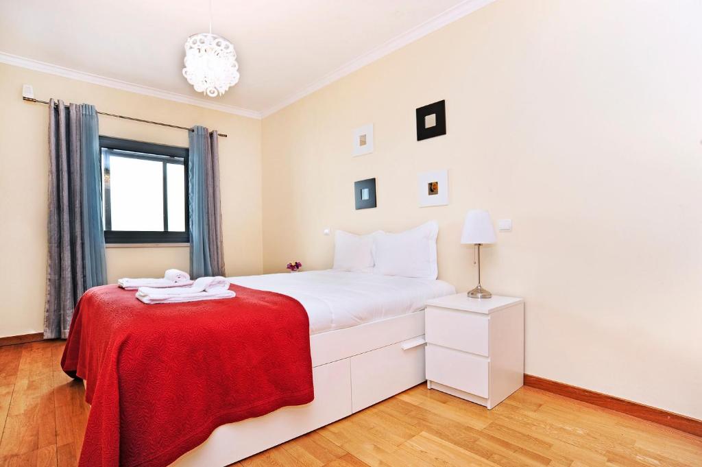 um quarto branco com um cobertor vermelho numa cama em Oeiras by the beach - Checkinhome em Oeiras