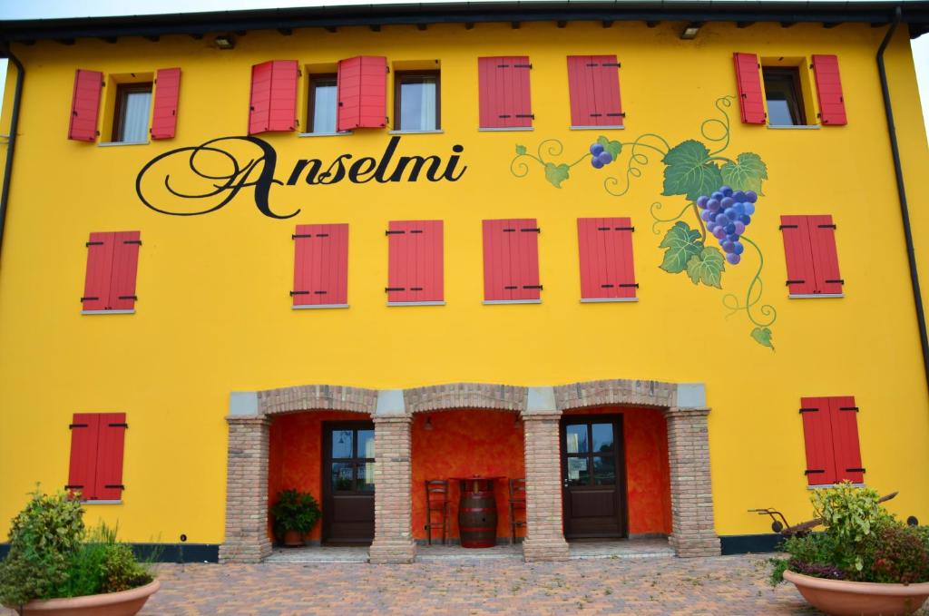 a yellow building with red windows and a sign on it at Là Di Anselmi in Palazzolo dello Stella