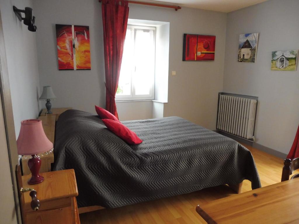 um quarto com uma cama com almofadas vermelhas e uma janela em Au Pied du Cognelot em Chalindrey