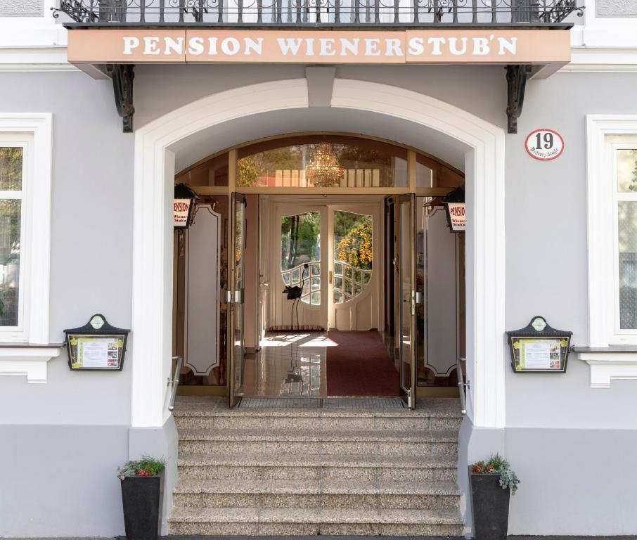 - une entrée dans un bâtiment blanc avec une porte d'entrée dans l'établissement Pension Wienerstub'n, à Baden