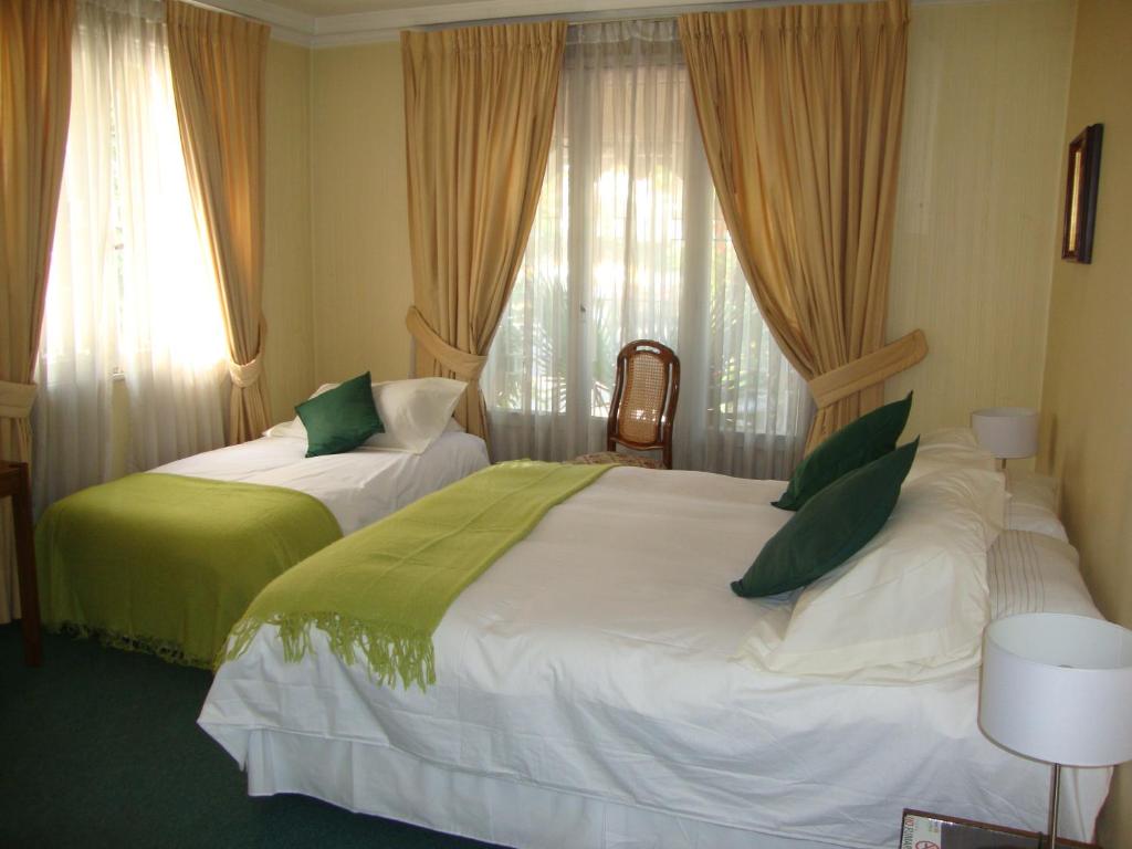 a hotel room with two beds with green pillows at Hotel Las Flores in Santiago