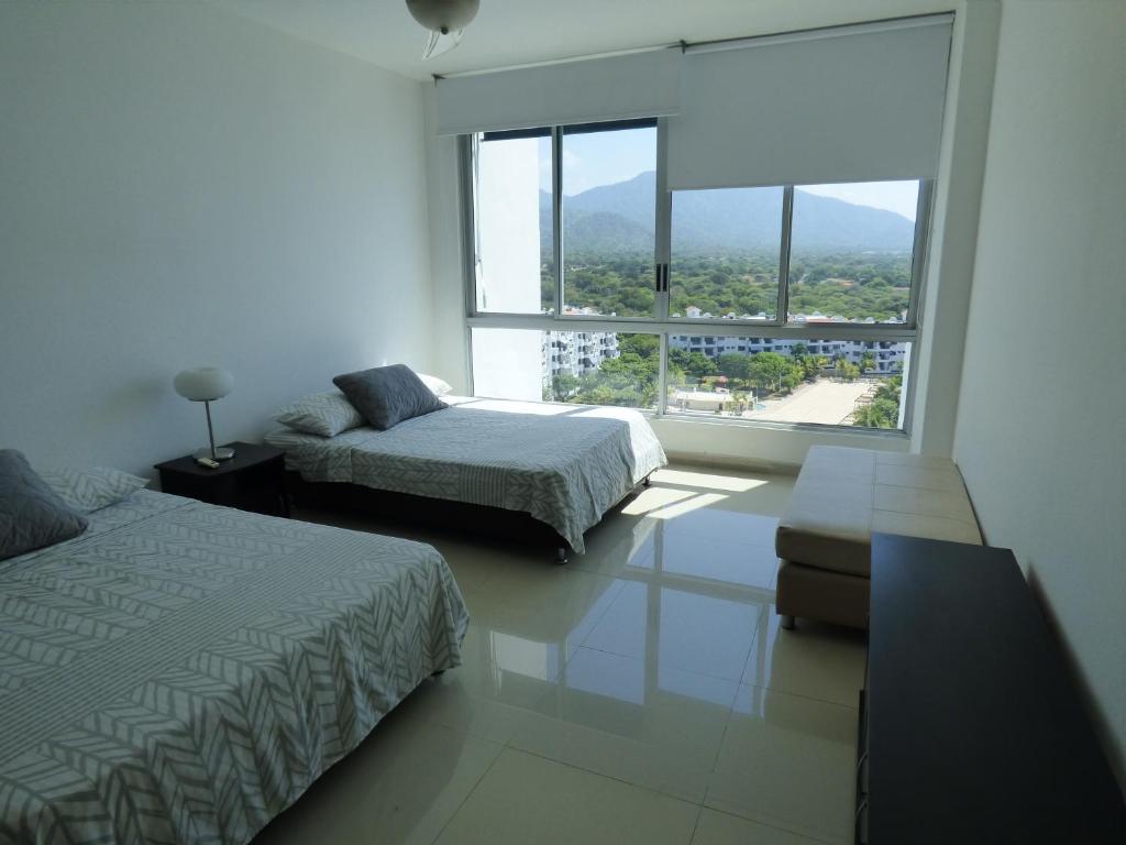 a bedroom with two beds and a large window at Costa Azul Suites 905 in Santa Marta