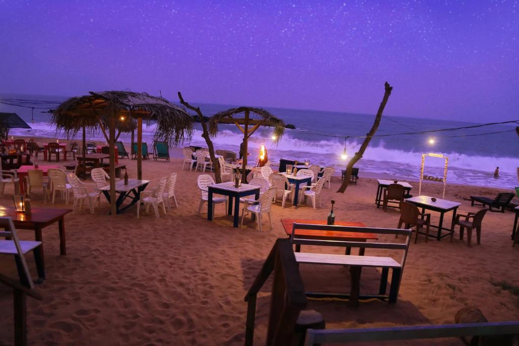 a group of tables and chairs on the beach at night at Golden Surfer Beach Hotel in Tangalle