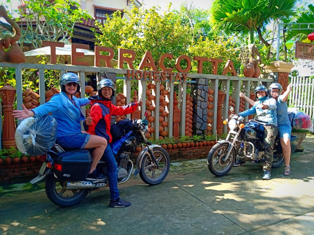 un grupo de personas montando motocicletas delante de un cartel en Terra Cotta Homestay en Hoi An