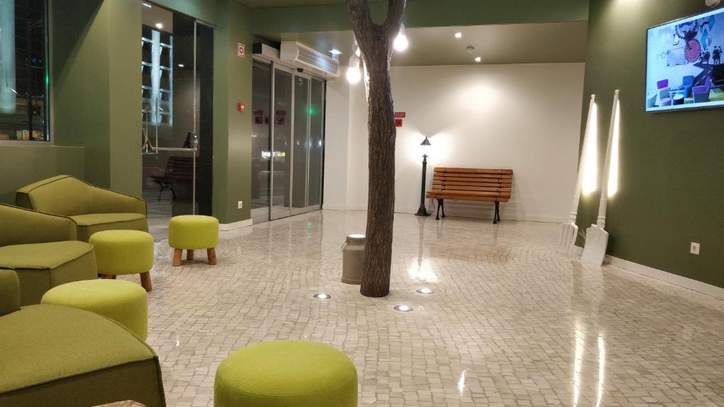 A bright lobby features lime-green lounge seating, a tiled floor and a central indoor tree.