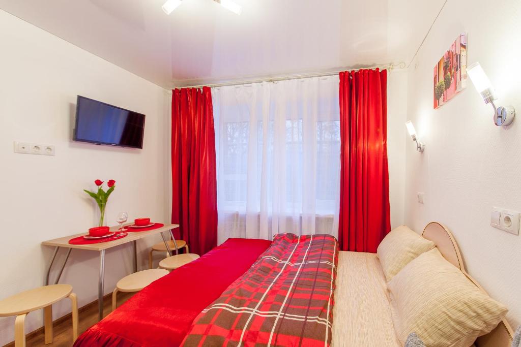 クラスノダールにあるСтудии на Бургасской K8rentのベッドルーム(赤いベッド1台、テーブル付)