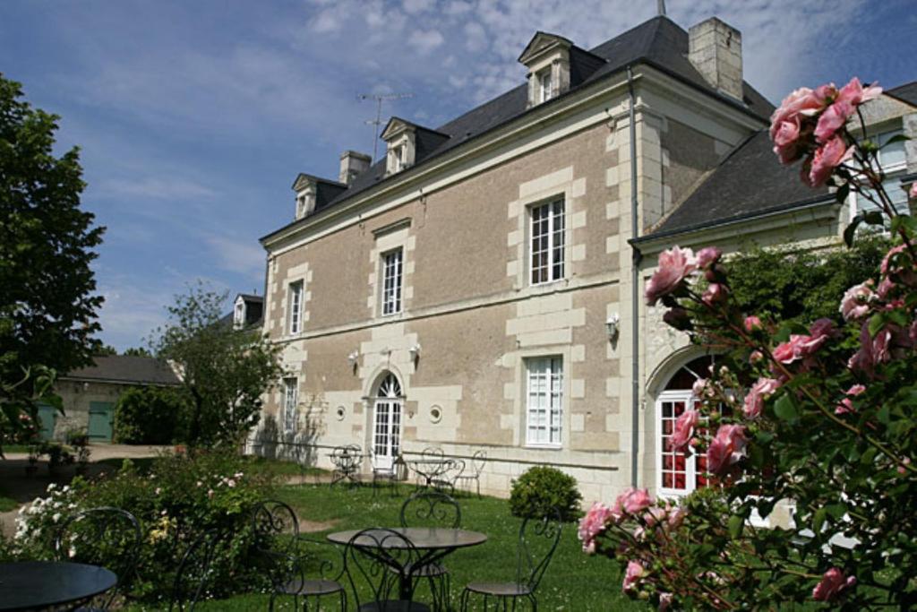 un grand bâtiment en briques avec des tables et des chaises dans une cour dans l'établissement Le Clos de Ligré, à Ligré