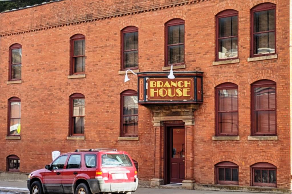 a red car parked in front of a brick building at The Branch House in Deadwood