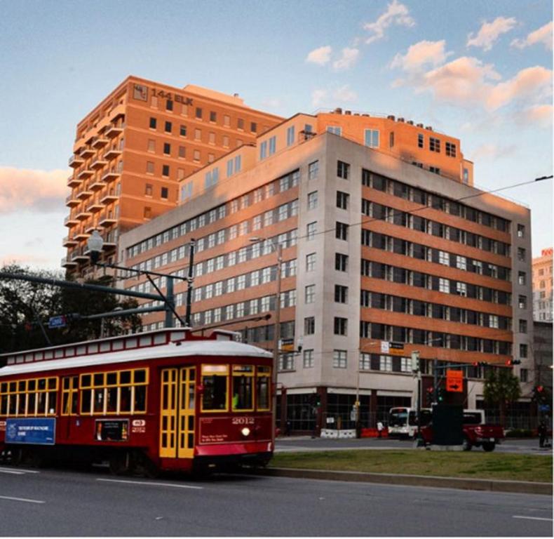 Hotel 2BR Spacious Condos Downtown New Orleans, a red trolley driving down a street in front of a building at 2BR Spacious Condos Downtown New Orleans in New Orleans