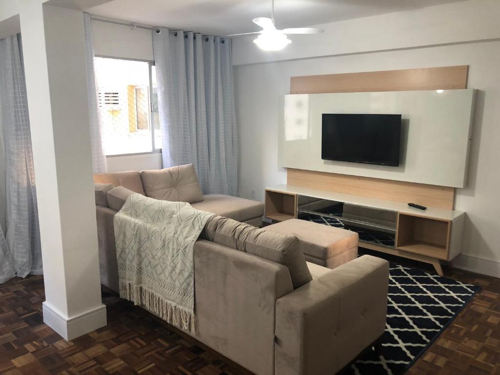 uma sala de estar com um sofá e uma televisão de ecrã plano em Prédio frente mar 3 quartos Balneário camboriú BrisaMarBC3 no Balneário Camboriú
