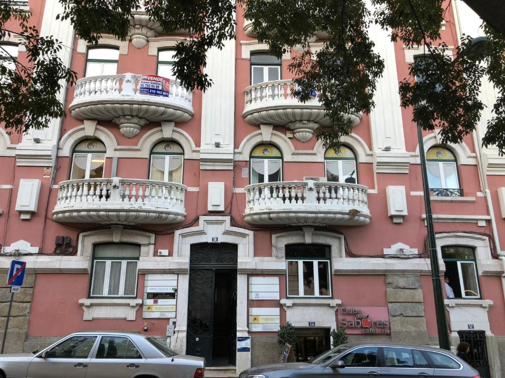 un bâtiment rose avec des balcons sur son côté dans l'établissement Be Lisbon Residence Marquês, à Lisbonne