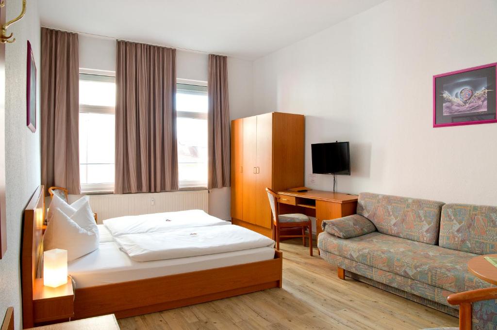 イェーナにあるホテル チューリンガー ホフのベッドとソファ付きのホテルルーム
