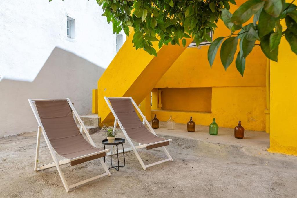 リスボンにあるBright & Spacious With Orange Tree Patio, by TimeCoolerの黄色い壁の前に椅子2脚とテーブル