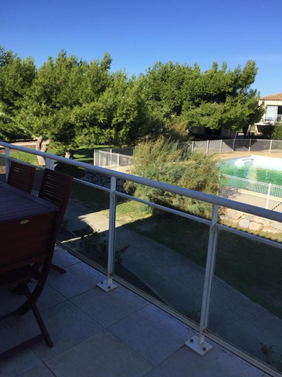 uma varanda com vista para uma piscina em T 3 appart les jardins du phœbus em Gruissan