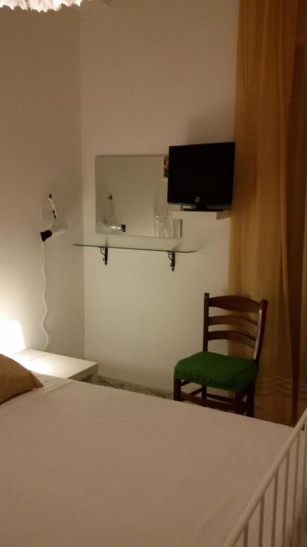 sypialnia z łóżkiem, krzesłem i telewizorem w obiekcie B&B Metropolitan Taranto w mieście Tarent