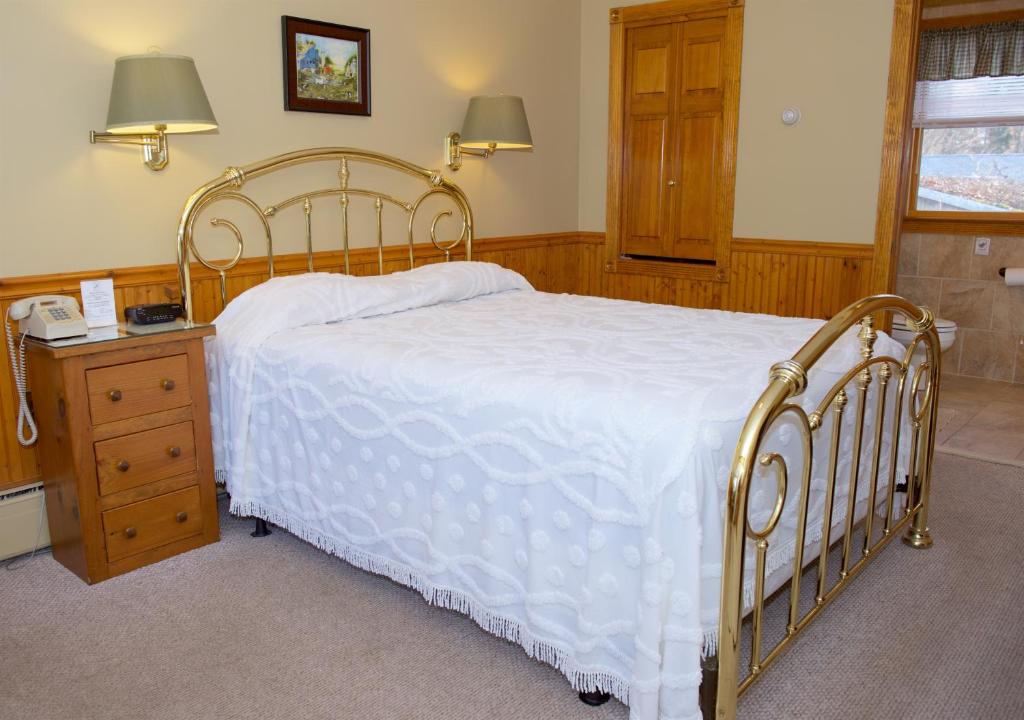 um quarto com uma cama branca e uma mesa de cabeceira com um telefone em Myer Country Motel em Milford
