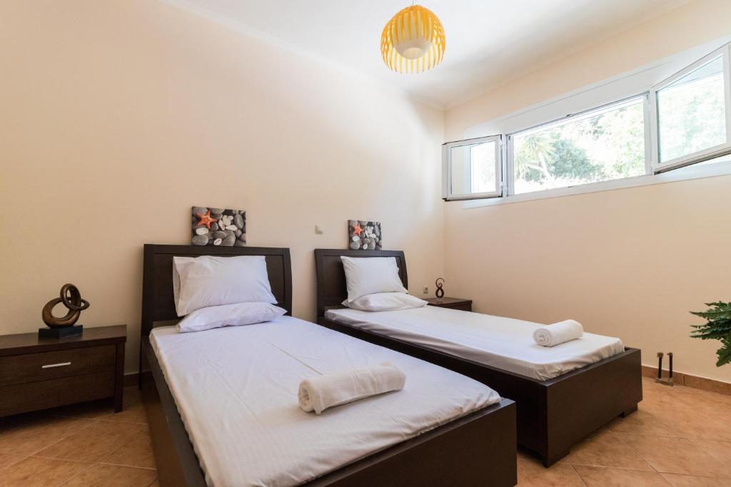 two beds in a room with two windows at Traditional Fishing Village Apartments in Boukari