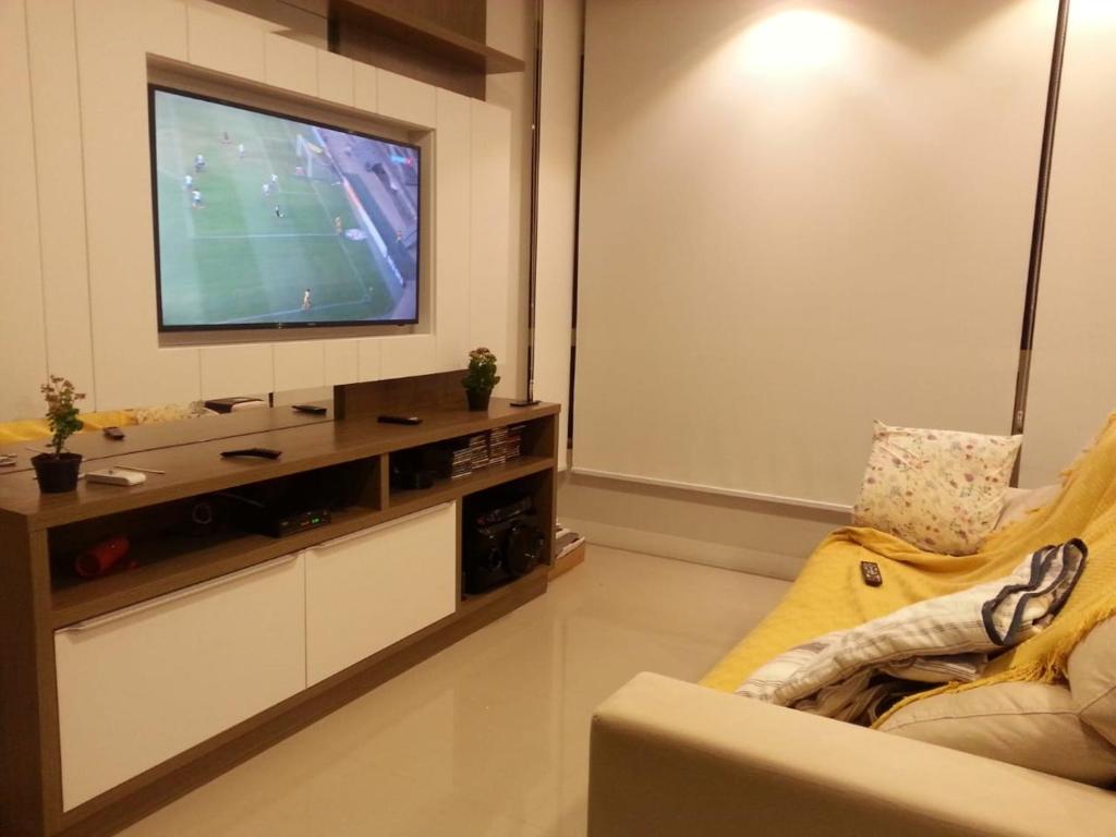 een woonkamer met een flatscreen-tv aan de muur bij quarto social privado ap compartilhado in Capão da Canoa