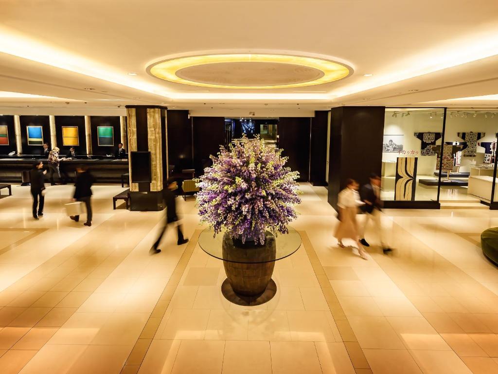 a lobby with a large vase with purple flowers in it at Sapporo Grand Hotel in Sapporo