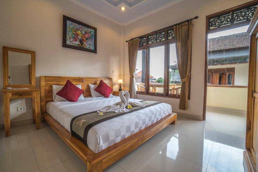 a bedroom with a bed and a large window at Baba Homestay in Ubud