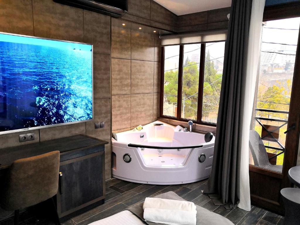 a bathroom with a tub and a large screen television at Piano Borracho Boutique Hotel Old Tbilisi in Tbilisi City
