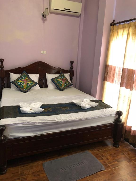 1 dormitorio con 1 cama con sábanas y almohadas blancas en Soutjai Guesthouse & Restaurant, en Vang Vieng