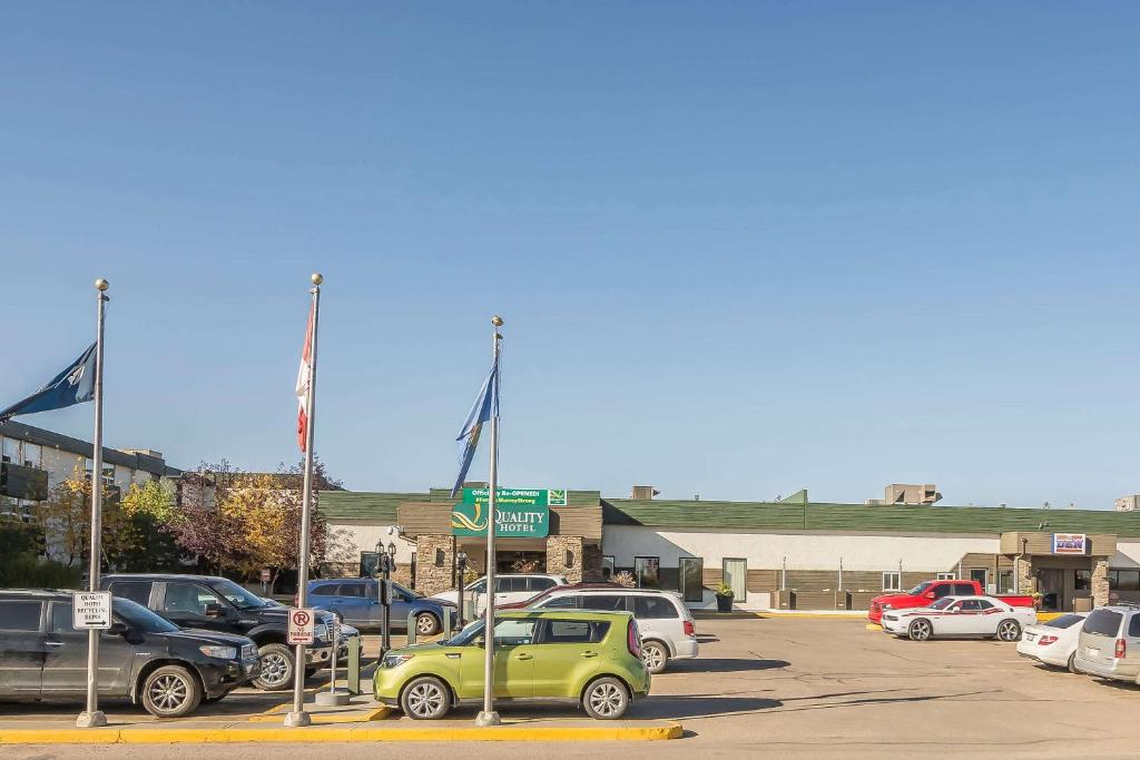 a parking lot with cars parked in front of a building at Quality Hotel & Conference Centre in Fort McMurray