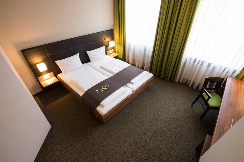 
a hotel room with a bed and a lamp at RiKu HOTEL Neu-Ulm in Ulm
