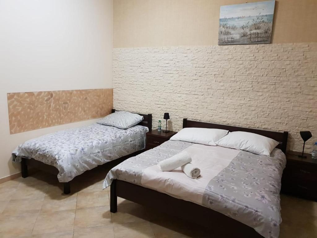 チェシンにあるTanzola Roomsのレンガの壁、ベッド2台が備わるベッドルーム1室が備わります。