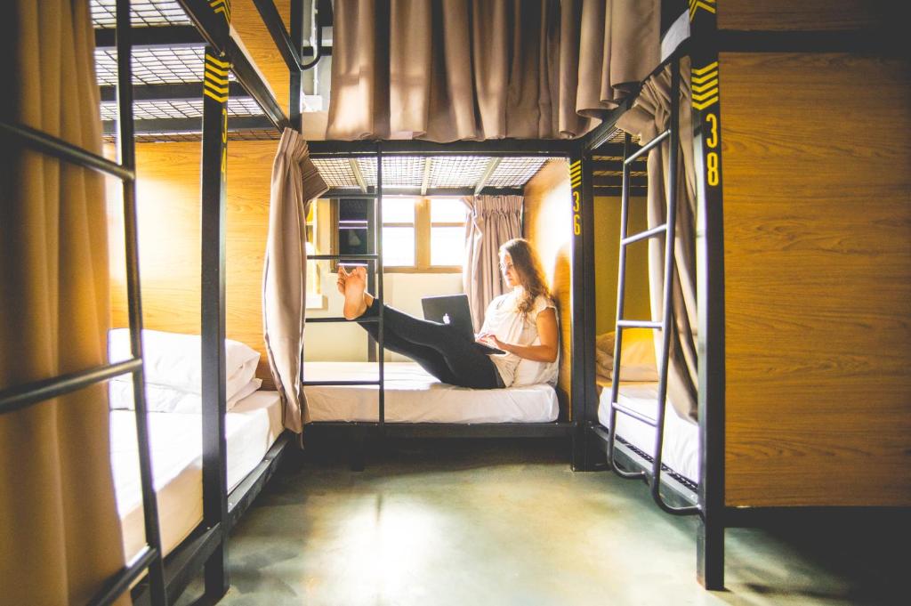 une femme assise sur un lit superposé dans l'établissement Traveller Bunker Hostel 1, à Cameron Highlands