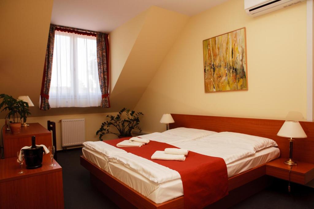 a bedroom with a bed with two towels on it at Lipa Hotel és Étterem in Szentgotthárd