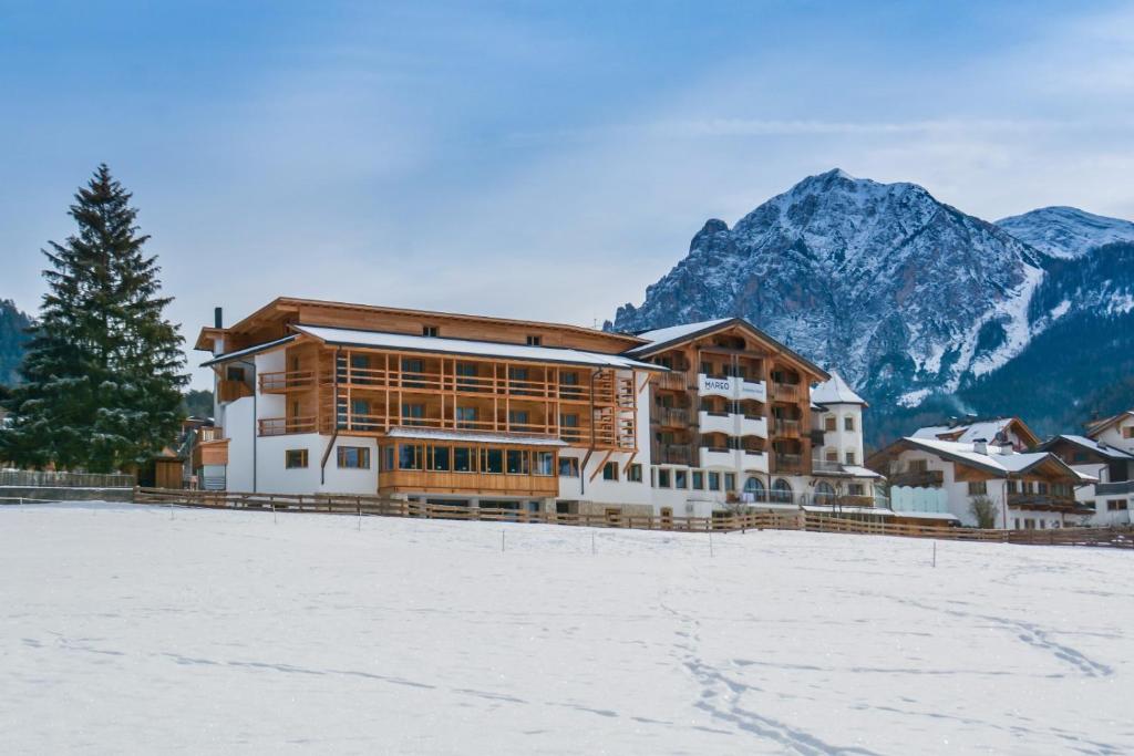 duży budynek ze śniegiem przed górą w obiekcie Dependance Hotel Mareo Dolomites w mieście San Vigilio di Marebbe