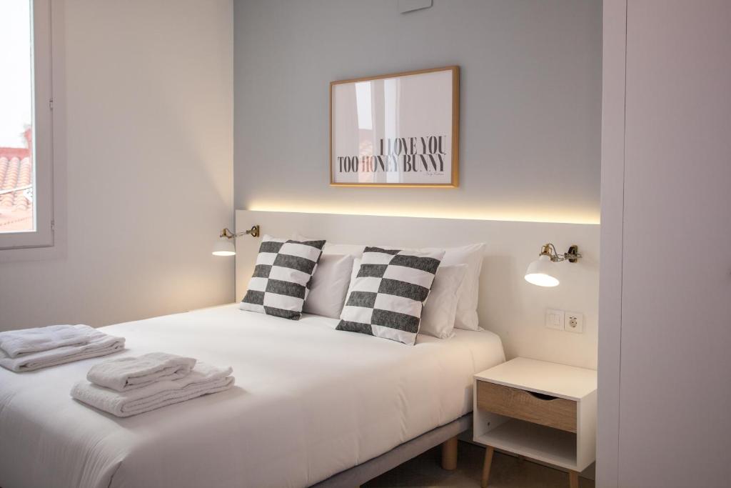 a white bedroom with a bed and a mirror at Gran Central Suites in Madrid
