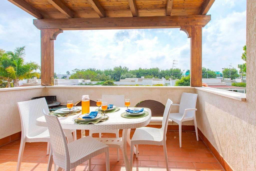 eine Terrasse mit einem Tisch und Stühlen auf dem Balkon in der Unterkunft Appartamento prato inglese sinistro Salento in Specchiolla 