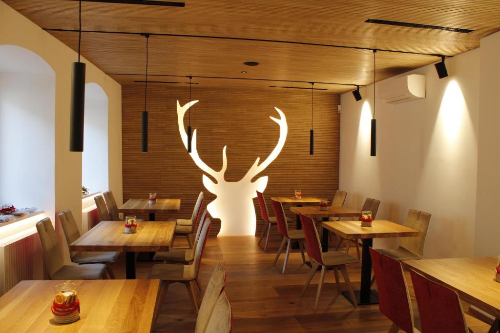 a restaurant with wooden tables and a large antlers on the wall at Gasthof Zum Hirschen Margreid in Magrè allʼ Adige