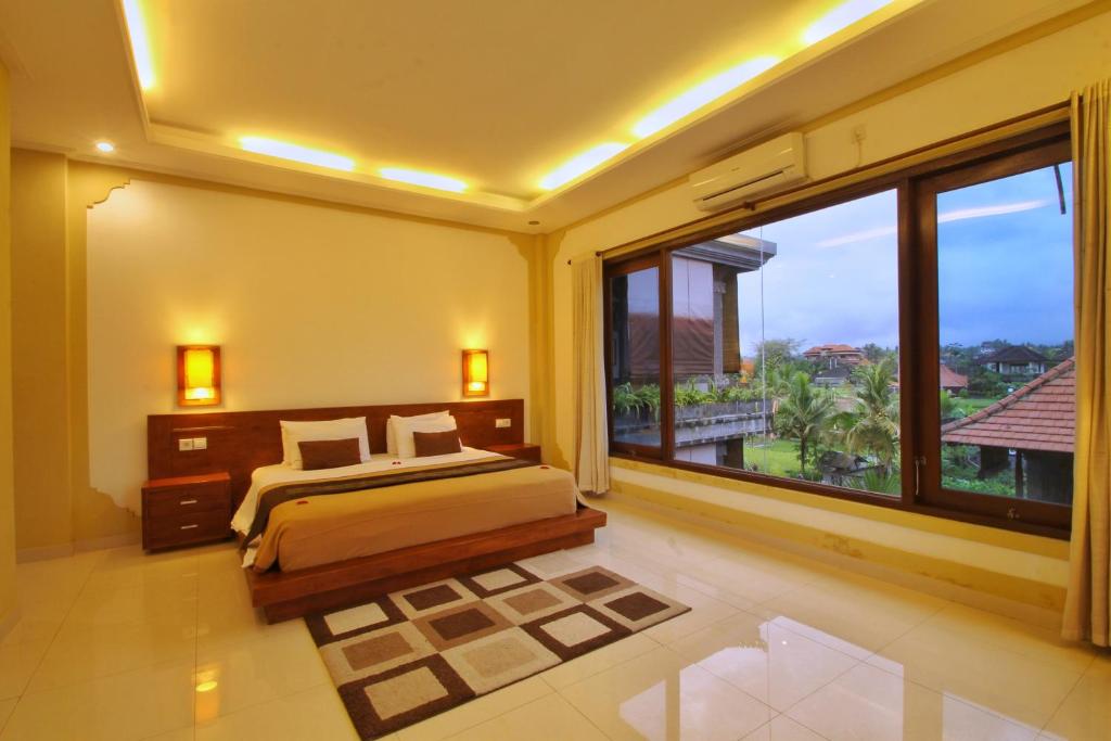 a bedroom with a bed and a large window at Hibiscus Cottages in Ubud
